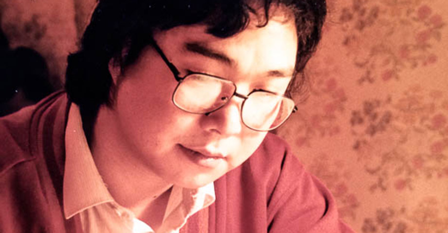 En porträttbild på Gui Minhai som sitter och skriver