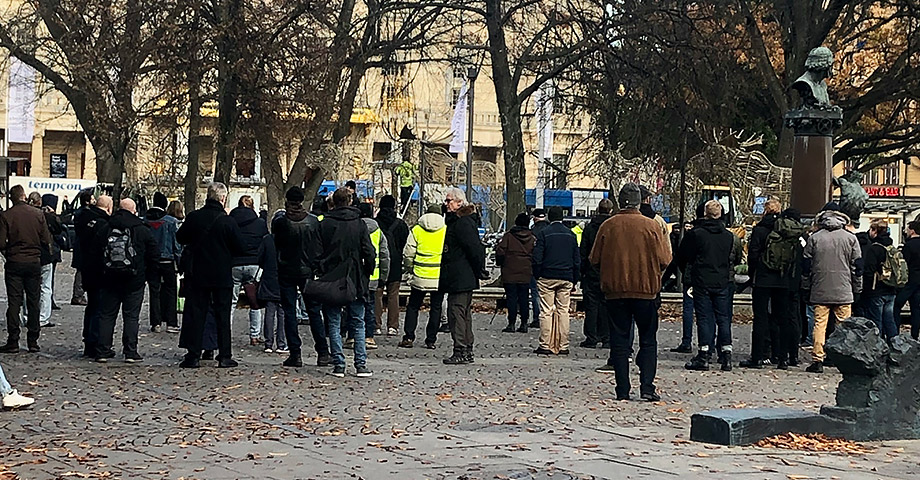 Nazistmanifestationen på Raoul Wallenbergs torg i Stockholm. De som deltar i manifestationen står med ryggarna mot kameran, man ser ett plakat skymta däremellan och i ena hörnet syns Raoul Wallenberg-monumentet