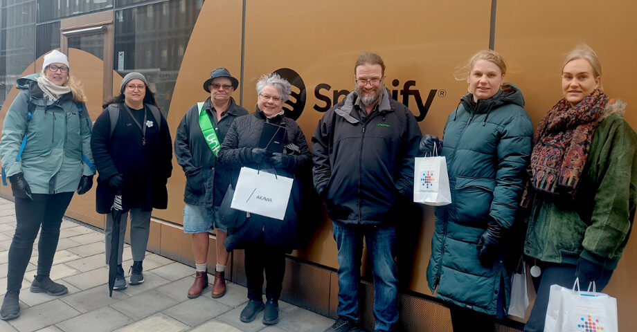 7 personer står framför Spotify-loggan